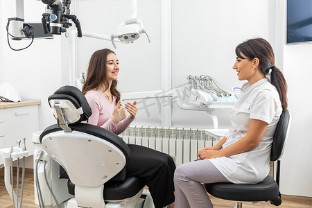 牙医治疗前在现代牙科诊所预约时与年轻患者交谈的女牙医