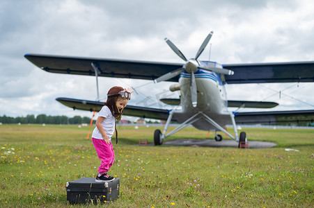 一个梦想成为飞行员的四人座私人飞机在球场上玩耍的可爱小女孩