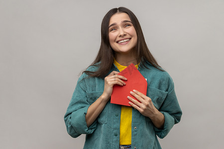 高兴的年轻女子拿着信封和阅读信件，脸上带着幸福的表情，被感动了。