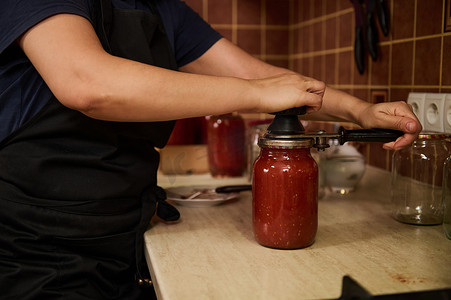 厨师使用封口机或特殊的封口钥匙，用新鲜罐装番茄酱 passata 盖上罐盖。