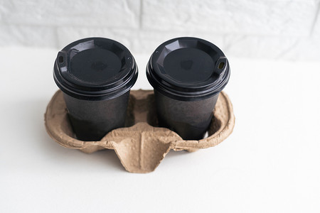 外卖纸咖啡杯放在木桌上的纸板架上，黑色背景，文字空间。