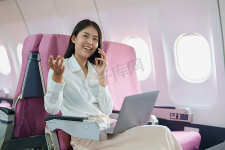 豪华飞机摄影照片_亚洲商务女性乘客坐在商务舱豪华飞机上，同时使用智能手机移动通话或视频会议和旅游概念工作