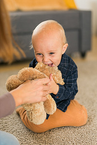 快乐的小熊摄影照片_快乐的蹒跚学步的男孩在家里玩她的泰迪熊 — 童年和儿童发展阶段的概念