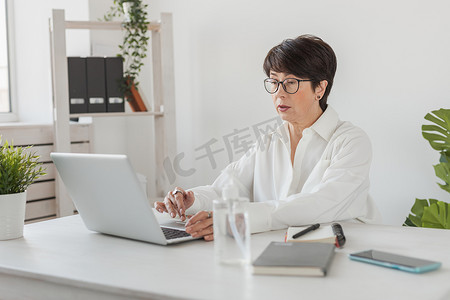 在办公室工作的女商人用笔记本电脑进行视频通话。