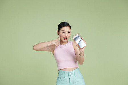 微笑的亚洲女性手持黑色空白设备屏幕智能手机的肖像，展示拇指手势