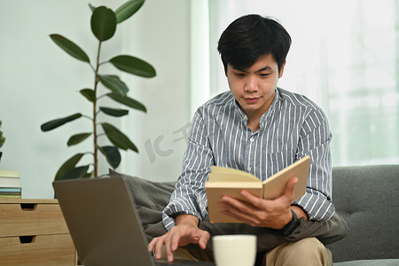 帅气的亚洲男性自由职业者使用笔记本电脑并在笔记本上检查他的工作计划