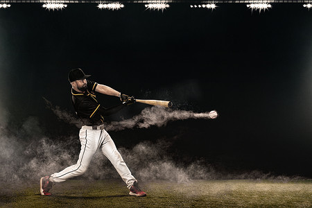 大棒球摄影照片_拿着球棒在大舞台上挥杆的棒球运动员。