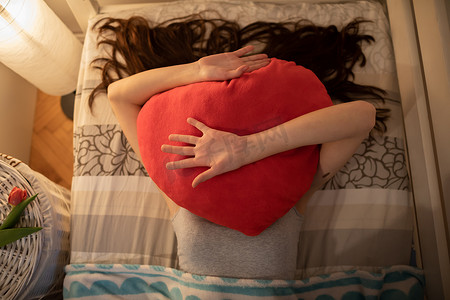 红色的心形抱枕枕在女孩的脸上。