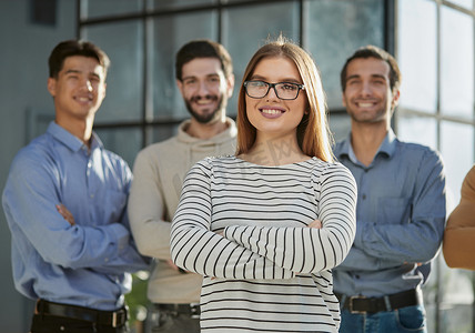 人员组成摄影照片_一个由四人组成的团队站在现代办公室里，前景是一位女性领导
