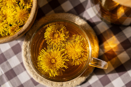 蒲公英花健康茶在玻璃茶壶和玻璃杯在桌上。