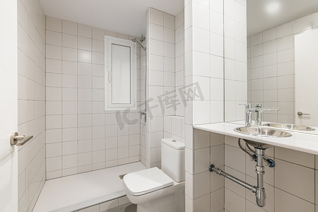 新装修的小家庭公寓内配有白色瓷砖淋浴、水槽和卫生间的舒适干净的新浴室。
