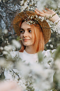 樱花中戴草帽的女人画像。