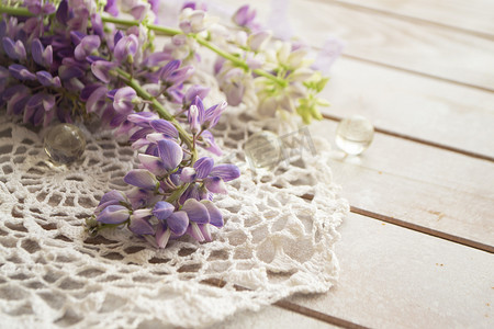 可爱的羽扇豆和复古蕾丝在质朴的白色木质背景上，采用浅色花卉贺卡。