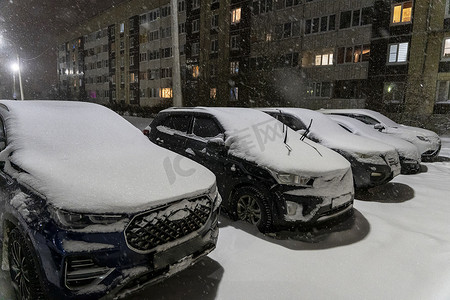 在院子里的一个开放停车场里，一排排停着积雪的汽车