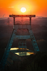 落山的太阳摄影照片_德国赫尔滕背景金色太阳落山的头架塔的垂直拍摄