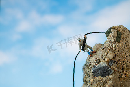 人物攀登摄影照片_微型人物：攀登岩石的徒步旅行者。