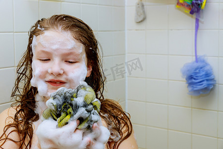 洗澡洗头摄影照片_可爱的小女孩在泡沫浴中洗头