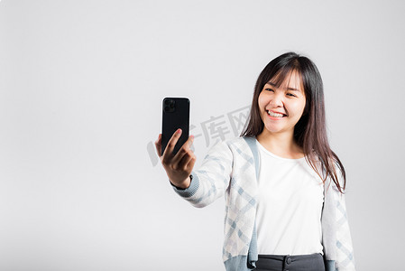 女人兴奋地拿着智能手机拍摄前置摄像头的自拍照片