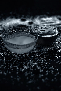 Ubtan/面罩/木尔塔尼米蒂面膜或漂白土在玻璃碗中的木质表面，由木尔塔尼米蒂和椰子油组成，用于补救或治疗晒黑。在木质表面上。