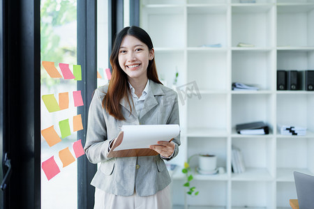 财务报表摄影照片_一位体贴的亚洲女商人在办公室查看财务报表并制定营销计划的肖像