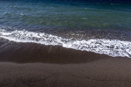 在沙滩上用黑色的火山岩沙滩冲浪。