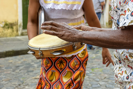 手鼓演奏者和一位穿着典型服装的女性在背景中跳舞
