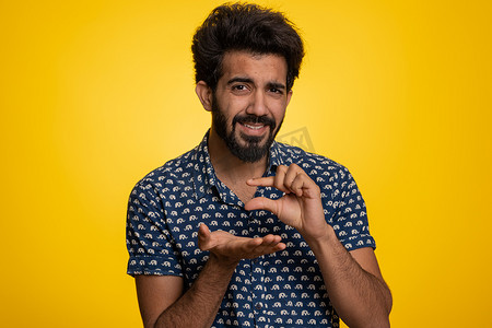 小号摄影照片_印度男子用怀疑的微笑摆出一点手势，显示最小尺寸的小号