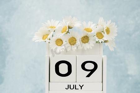 7 月用雏菊花装饰的白色立方体日历