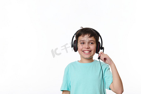 聪明的西班牙裔少年，戴着耳机的学童，可爱地笑着，露出欢快的露齿微笑，与世隔绝在白色