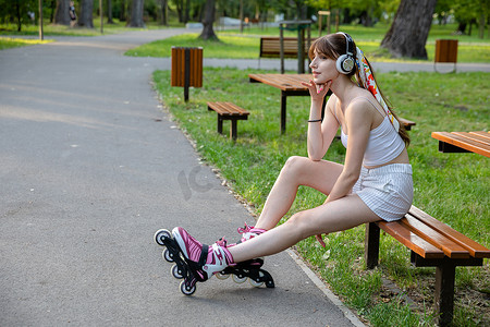 坐在公园长椅上的年轻女子听音乐