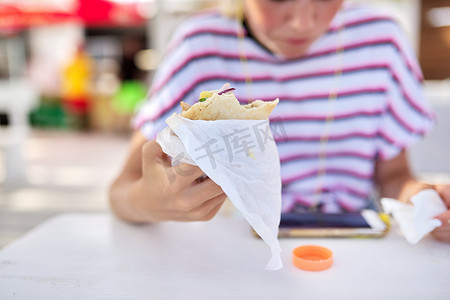 吃三明治、汉堡的少女，戴着耳机看着智能手机屏幕