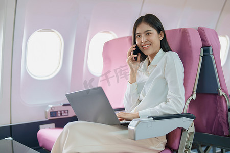 亚洲商务女性乘客坐在商务舱豪华飞机上，同时使用智能手机移动通话或视频会议和旅游概念工作