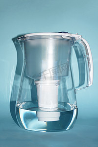 塑料罐透明摄影照片_蓝色背景中用于过滤水的水壶