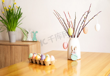 复活节装饰一束柳树枝，上面有彩蛋、鲜花和兔子。