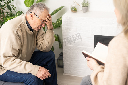 身穿制服的老年男性患者和年轻女性护理人员医护人员拿着剪贴板记录个人信息谈话，听客户讲述健康投诉、护理支持护理理念