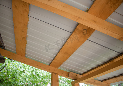 异形背景板背景板摄影照片_带金属波纹板的木屋顶椽子的特写，底视图