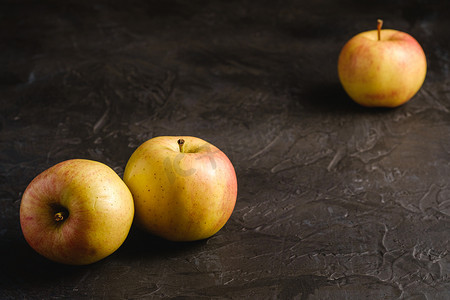 三鲜米粉摄影照片_深黑色纹理背景中鲜甜的三个苹果