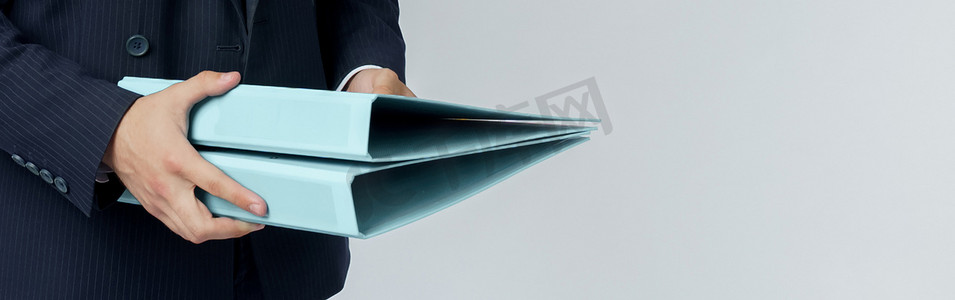 套装背景摄影照片_身穿蓝色西装的商人手里拿着一个白色背景的文件夹。