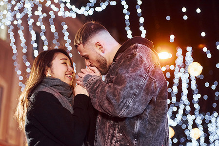 拥抱新年摄影照片_快乐的多种族夫妇一起在城市户外庆祝新年