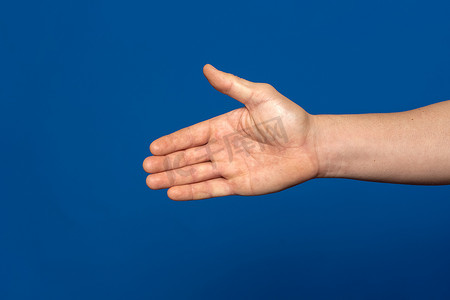 伸出手摄影照片_男人伸出手来与蓝色背景上孤立的握手。