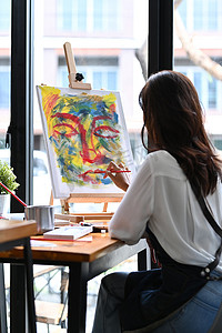 国旗图片涂色摄影照片_在艺术工作室的画布上的女艺术家绘画图片的后视图。