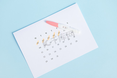 在白色日历上查看阳性妊娠试验，最后一次月经日期标记为蓝色背景。