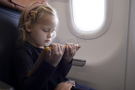 专注的女孩在飞机上看平板电脑上的视频