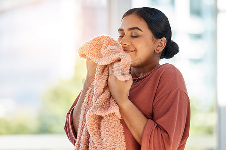 做起来摄影照片_女人在洗完衣服、打扫卫生和做家务后，闻到干净的衣服、毯子或织物的味道，闻到屋子里清新干净的气味。