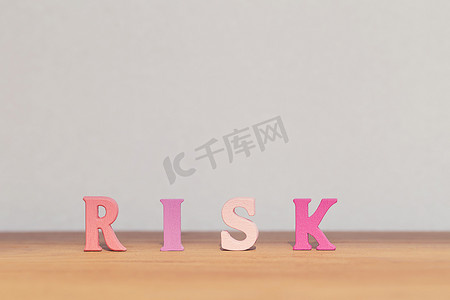 经济下行摄影照片_在桌子上安排木制字母单词风险。