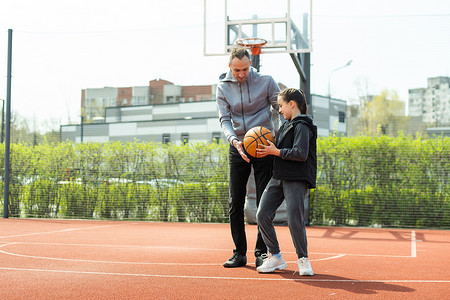 父亲和十几岁的女儿在球场外打篮球