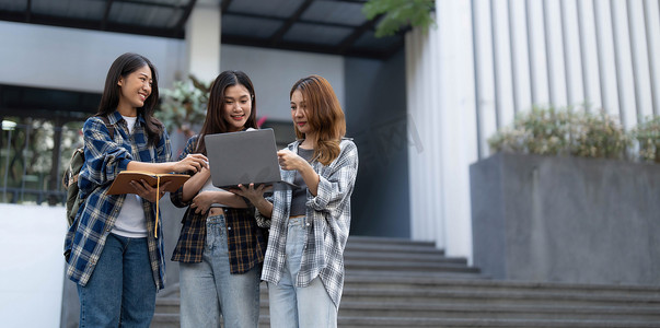 一群亚洲大学生在户外草地上阅读书籍和辅导特殊课程。