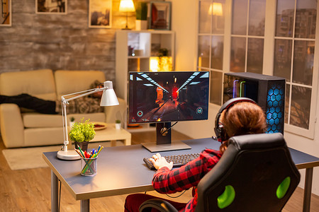 深夜在客厅玩功能强大的电脑 PC 的女性游戏玩家的后视图