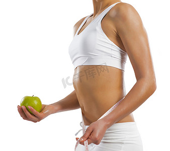 拿着一个绿色苹果的年轻运动妇女
