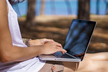 自由职业女性在海边松林中使用笔记本电脑度假工作的特写、智能工作生活方式概念主题和生活选择